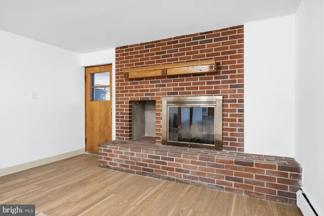 a view of an empty room with wooden floor and fireplace