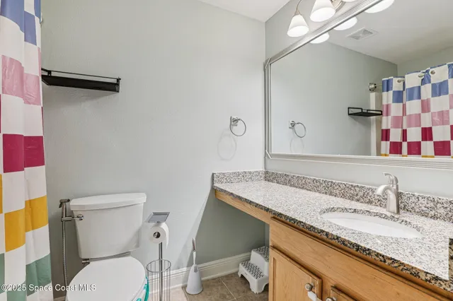 a bathroom with a granite countertop toilet sink and mirror