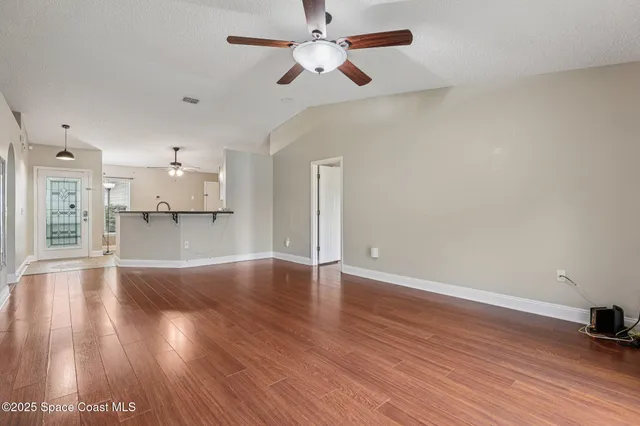 a view of empty room with wooden floor and ceiling fan