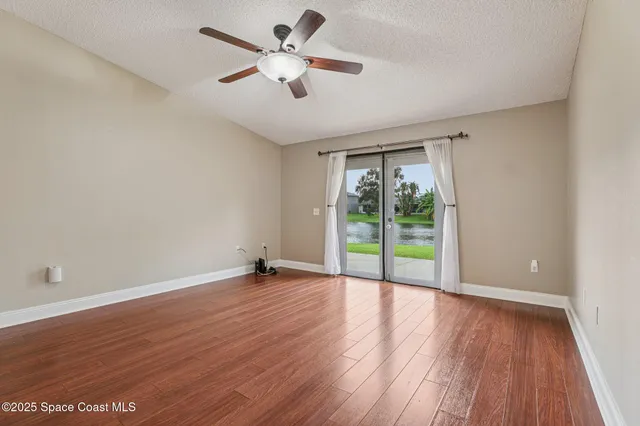 a view of an empty room with a window and wooden floor