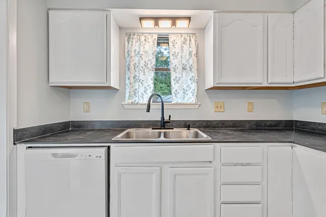 a kitchen with granite countertop a sink and white cabinets