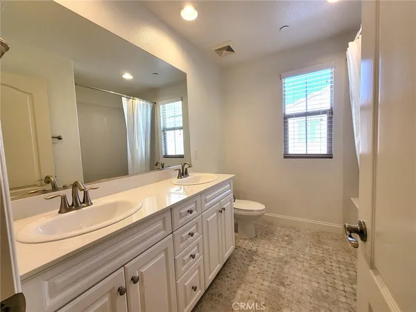 a spacious bathroom with a double vanity sink toilet mirror and windows