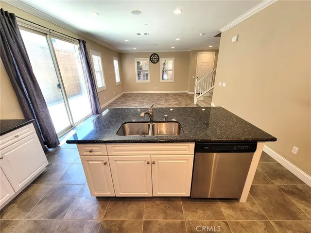 a kitchen with granite countertop a sink and white cabinets