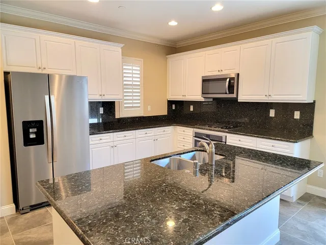 a kitchen with stainless steel appliances granite countertop a sink a stove top oven a counter space and cabinets