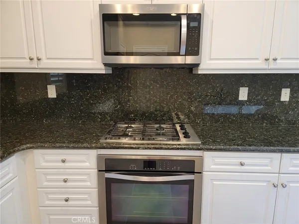 a kitchen with granite countertop white cabinets and black appliances
