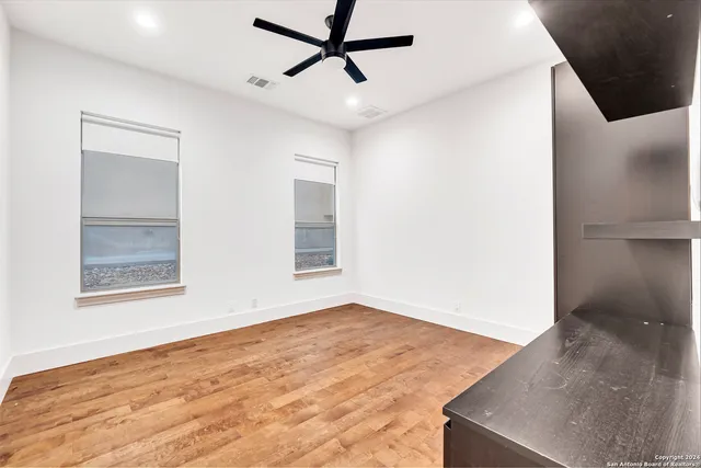 a view of empty room with wooden floor and fan