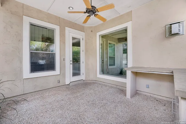 an empty room with chandelier fan and windows