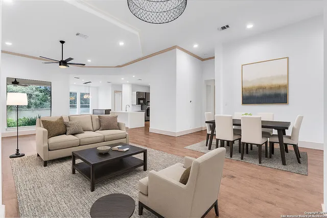 a living room with furniture kitchen view and a wooden floor