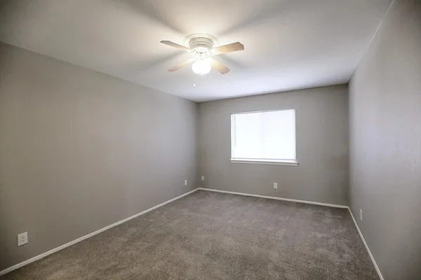 an empty room with a window and a fan