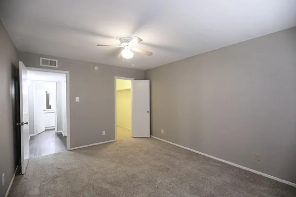 an empty room with closet and a chandelier fan