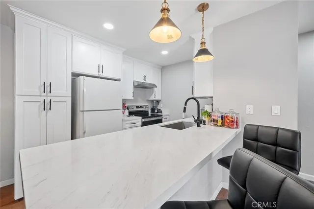 a kitchen with stainless steel appliances granite countertop a refrigerator a sink dishwasher a stove a dining table and chairs with wooden floor