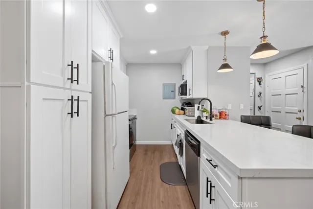 a kitchen that has a lot of cabinets a sink and a wooden floor