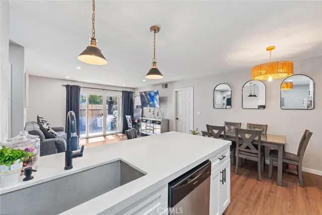 a kitchen with stainless steel appliances granite countertop a stove a sink a dining table and chairs with wooden floor