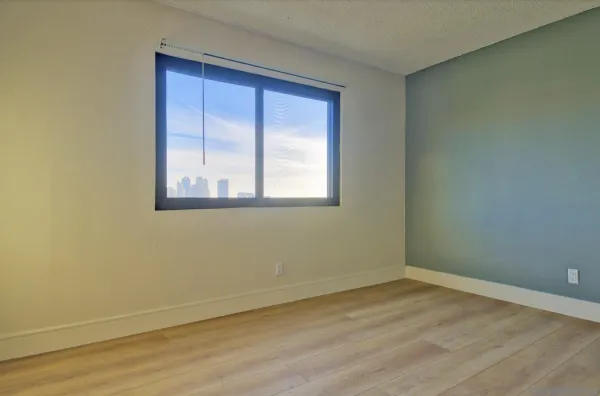 a view of an empty room with wooden floor and a window