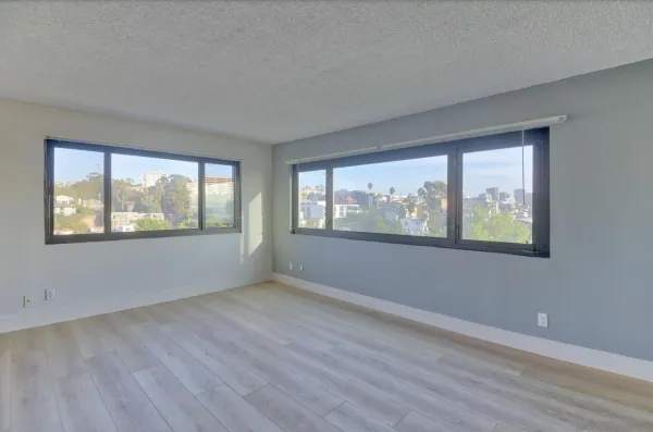 a view of an empty room with wooden floor and a window