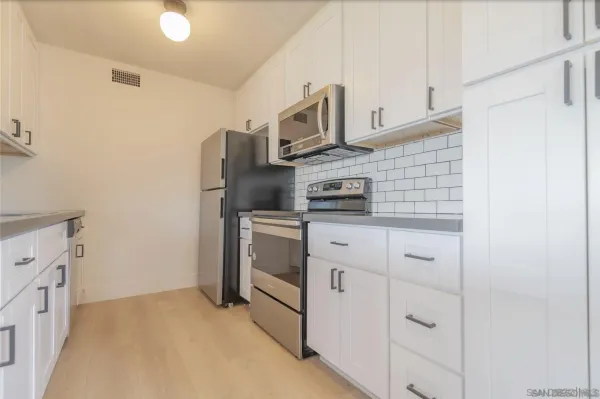 a kitchen with stainless steel appliances white cabinets and a refrigerator