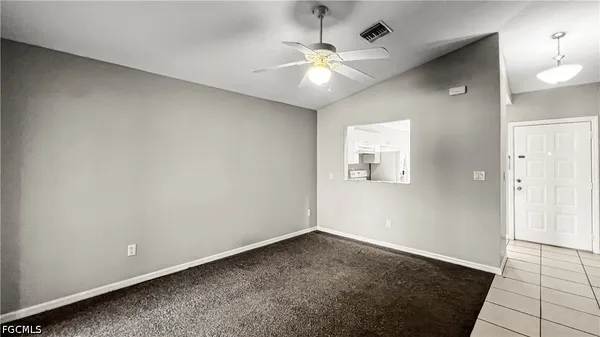 an empty room with a chandelier fan and windows