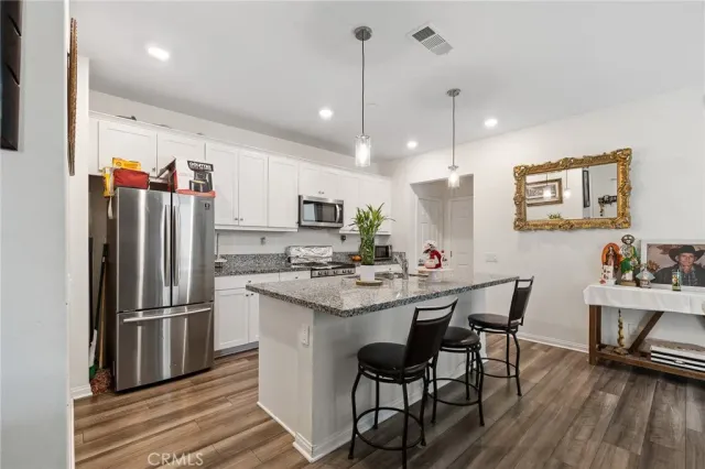 a kitchen with stainless steel appliances a dining table chairs refrigerator and microwave