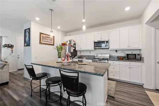 a kitchen with stainless steel appliances granite countertop a stove a sink a microwave a center island and furniture