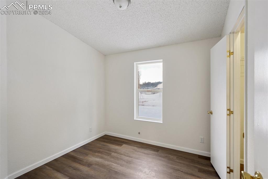 16625 Roller Coaster Road Colorado Springs, CO 80921 - Photo 12 of 44 an empty room with wooden floor and windows