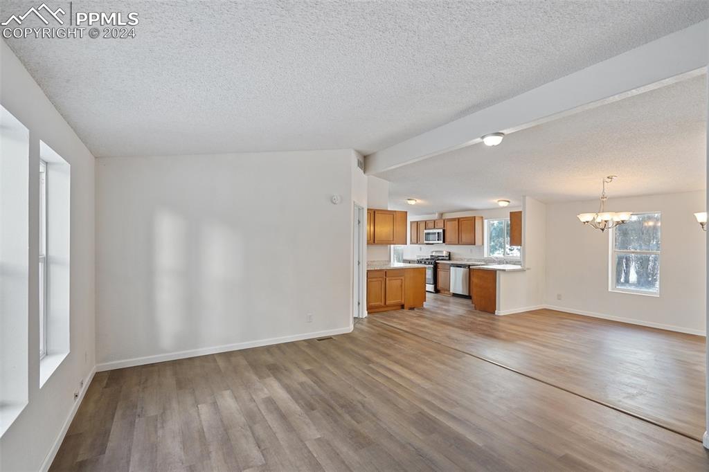 16625 Roller Coaster Road Colorado Springs, CO 80921 - Photo 17 of 44 an empty room with wooden floor and a kitchen