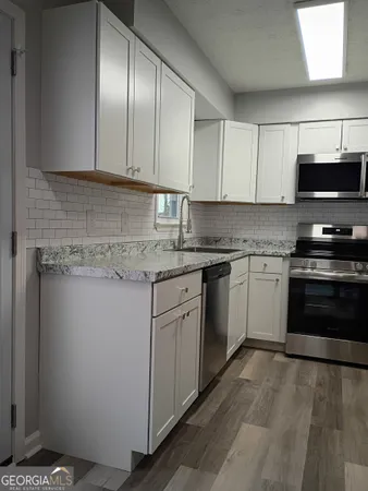 a kitchen with granite countertop a stove top oven sink and cabinets