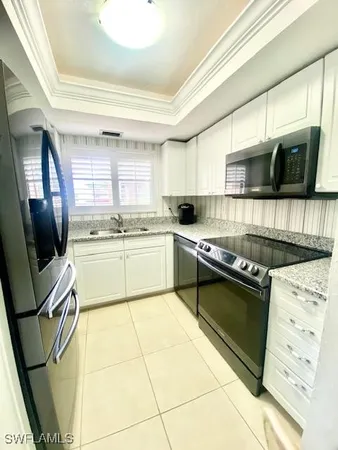 a kitchen with stainless steel appliances kitchen island granite countertop a sink dishwasher a stove a microwave oven with granite countertops and cabinets