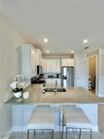 a large kitchen with kitchen island a sink a stove a refrigerator and white cabinets