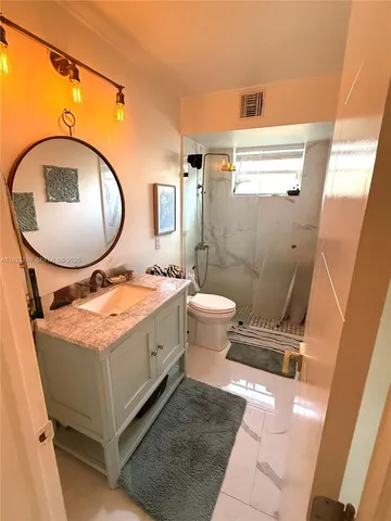 a spacious bathroom with a granite countertop toilet a sink and a mirror