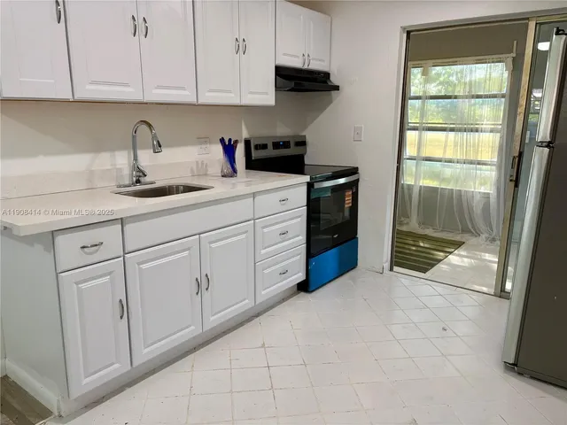 a kitchen with granite countertop white cabinets and sink