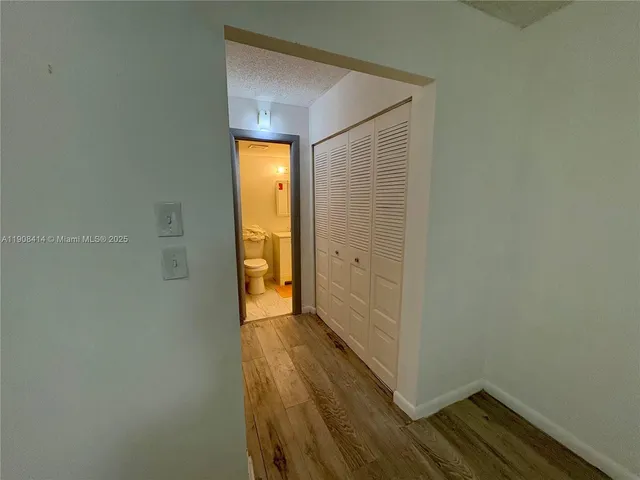 a view of a hallway with wooden floor and a bathroom