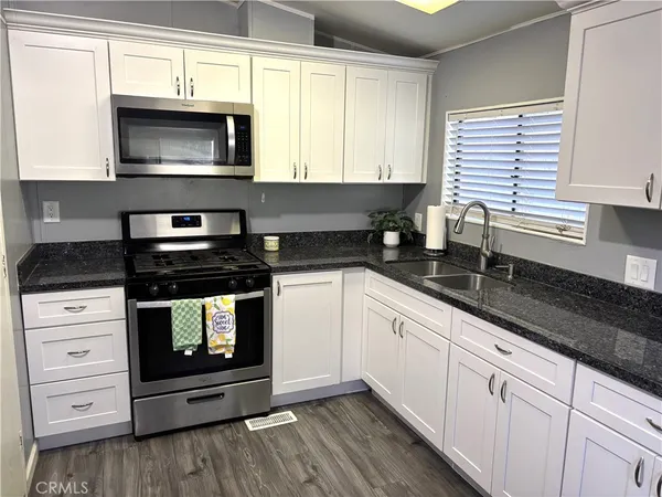 a kitchen with stainless steel appliances granite countertop white cabinets granite counter tops and a window