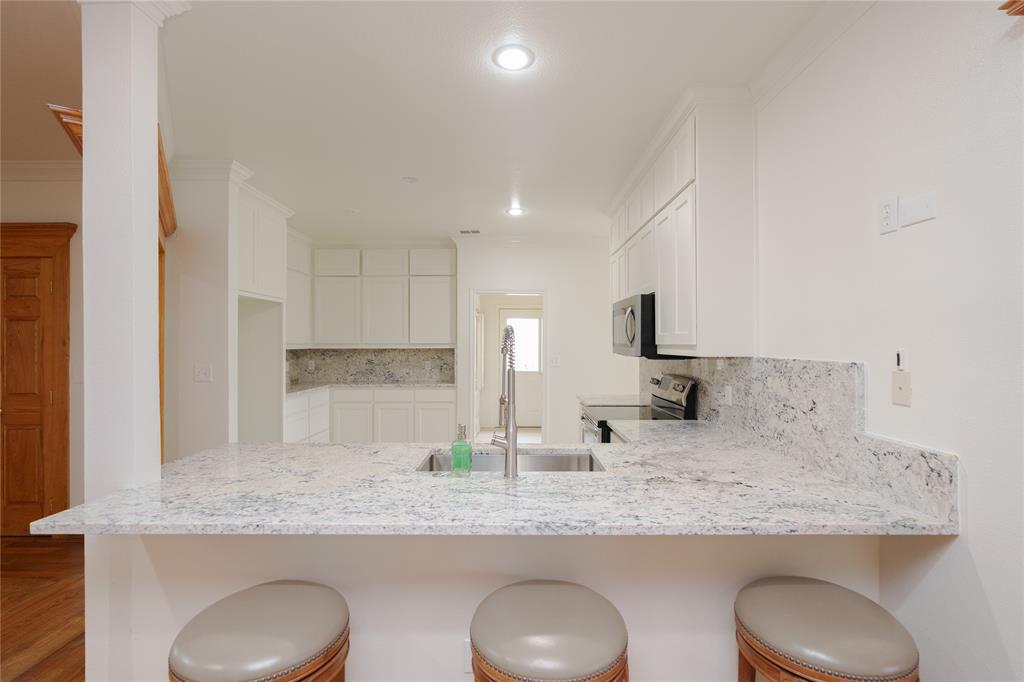 364 Parker Road, Unit A Van Alstyne, TX 75495 - Photo 14 of 39 Kitchen featuring a spacious bar with seating, a stainless steel undermount sink, white cabinetry, integrated stainless steel appliances, recessed lighting, and stone countertops