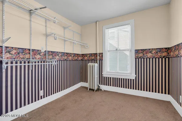 an empty room with chandelier fan and windows