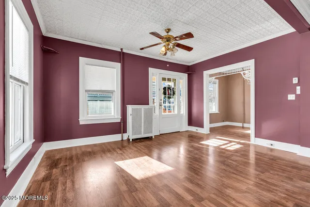 a view of an empty room with a window and wooden floor