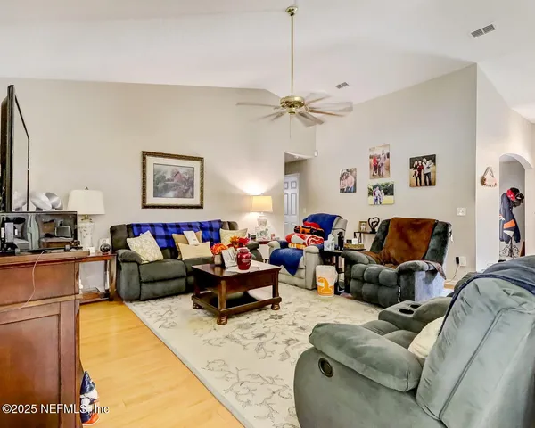 a living room with furniture kitchen view and a chandelier