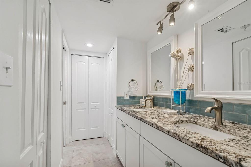 14600 Gulf Boulevard, Unit 102 Madeira Beach, FL 33708 - Photo 16 of 46 a bathroom with granite countertop a sink and a mirror