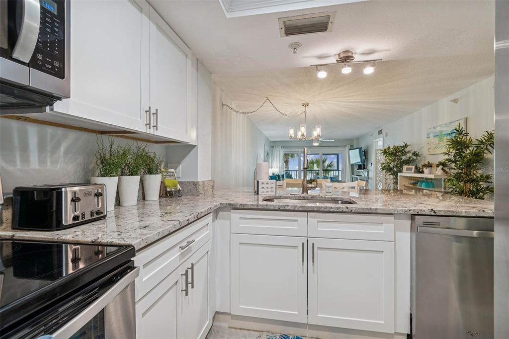 14600 Gulf Boulevard, Unit 102 Madeira Beach, FL 33708 - Photo 5 of 46 a kitchen with stainless steel appliances granite countertop a sink and cabinets