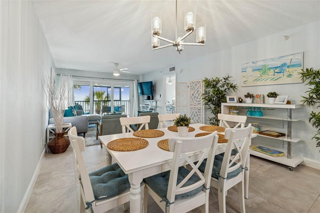 14600 Gulf Boulevard, Unit 102 Madeira Beach, FL 33708 - Photo 7 of 46 a view of a dining room and livingroom with furniture wooden floor a rug a painting and a chandelier