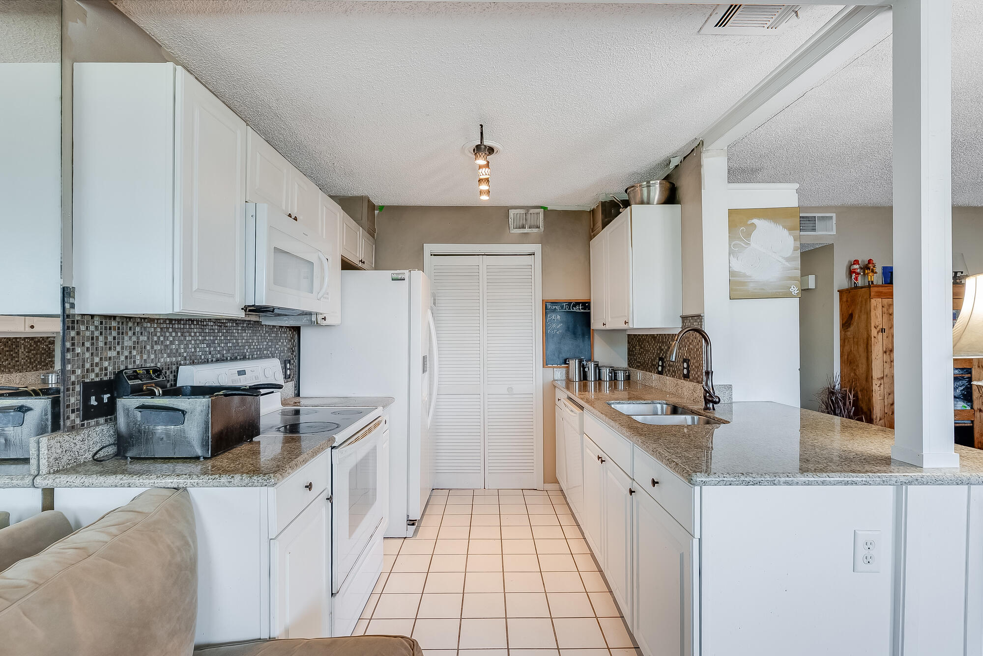 200 Pensacola Beach Road, Unit D2 Gulf Breeze, FL 32561 - Photo 12 of 38 a large white kitchen with stainless steel appliances granite countertop a stove and a sink