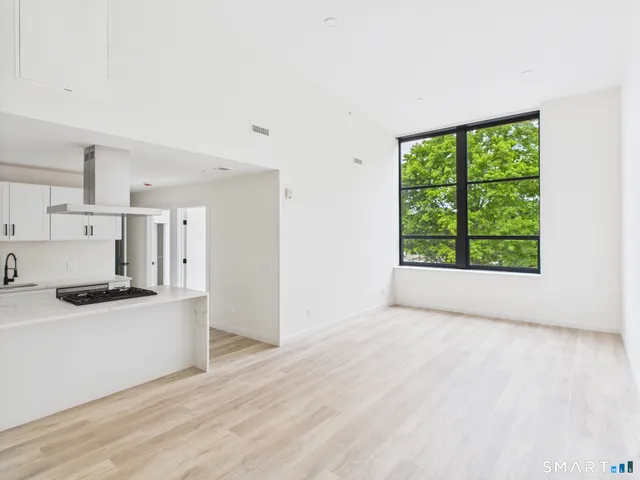 a kitchen with stainless steel appliances a stove top oven a refrigerator a sink and white cabinets with wooden floor