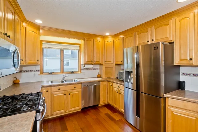 a kitchen with stainless steel appliances a refrigerator a sink and wooden floors