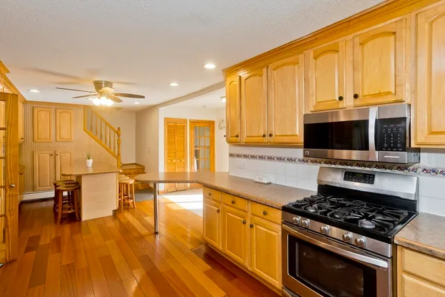 a kitchen with stainless steel appliances a stove a sink dishwasher and a microwave with wooden floor