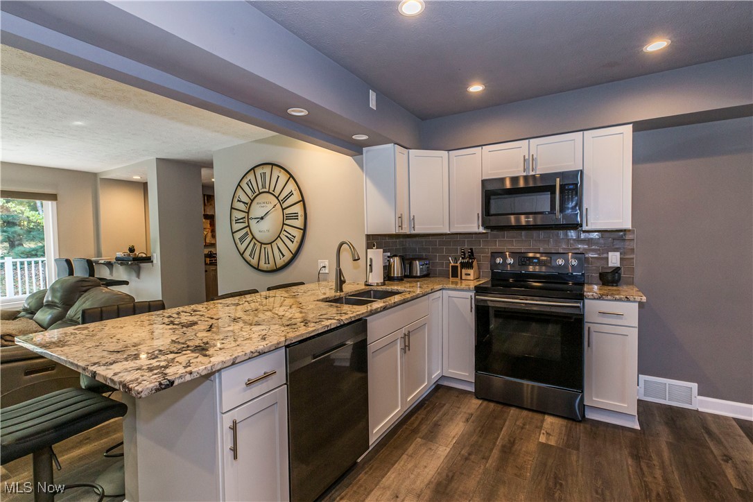2430 Rockside Road Independence, OH 44131 - Photo 46 of 46 Kitchen with stainless steel appliances, light stone countertops, open floor plan, white cabinetry, and recessed lighting