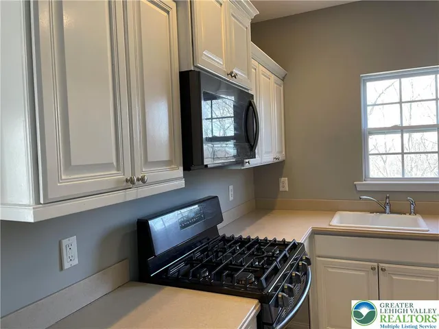 a kitchen with stainless steel appliances a stove a sink and a microwave