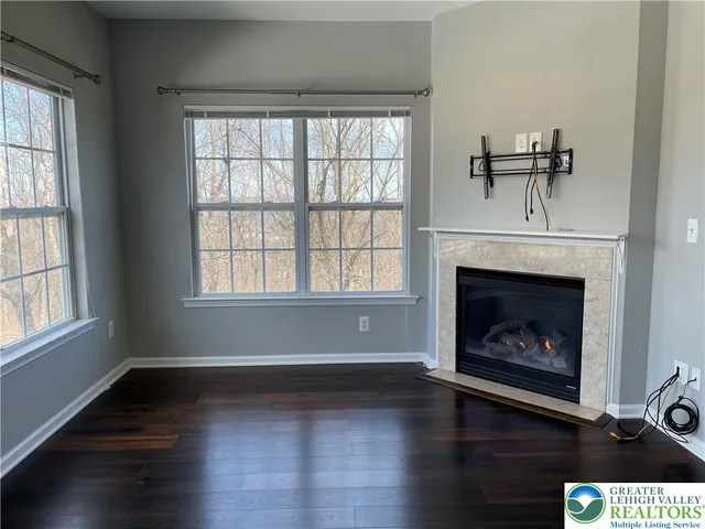 an empty room with wooden floor fireplace and window