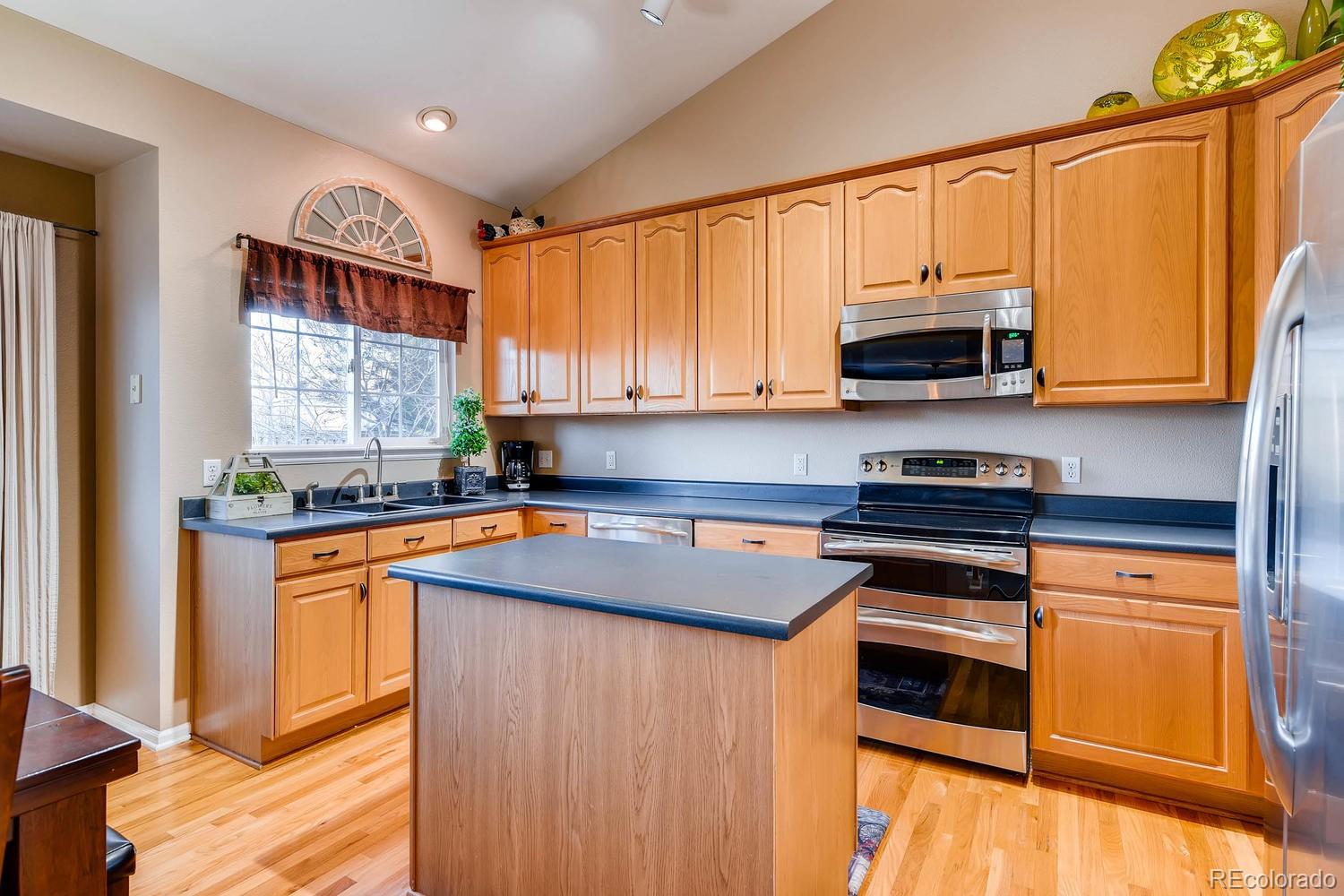 9825 South Thornbury Way Highlands Ranch, CO 80129 - Photo 6 of 27 a kitchen with stainless steel appliances a stove a sink and a microwave