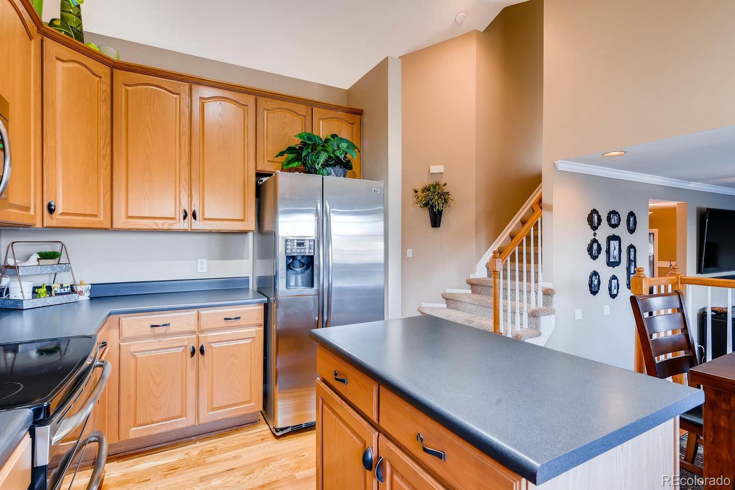 9825 South Thornbury Way Highlands Ranch, CO 80129 - Photo 8 of 27 a kitchen with stainless steel appliances granite countertop a refrigerator a stove and a wooden floors