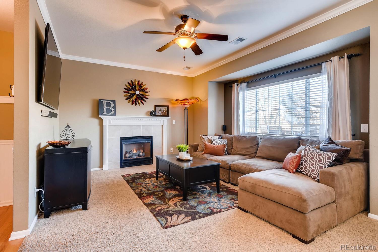 9825 South Thornbury Way Highlands Ranch, CO 80129 - Photo 10 of 27 a living room with furniture a chandelier and a fireplace