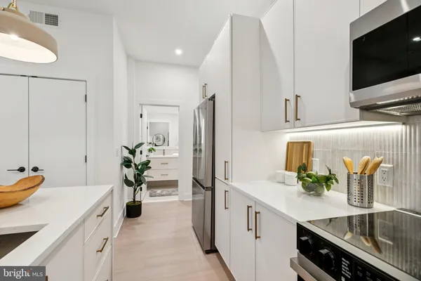 a spacious kitchen with stainless steel appliances a sink and a microwave